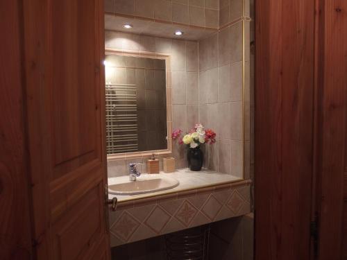 une salle de bain avec un lavabo et un vase de fleurs dans l'établissement L'Embrune, à Tignes