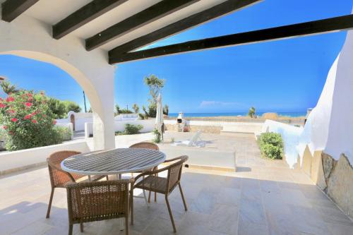 a patio with a table and chairs and the ocean at Urbanización El Oasis, 20 Villas en 1ª Línea Playa in Denia