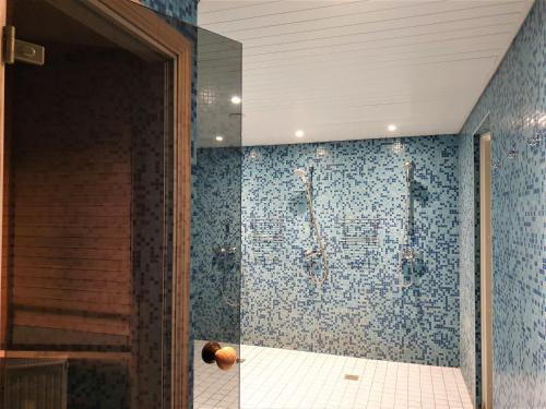 a bathroom with a shower with blue tiles at Nuustaku Villa in Otepää