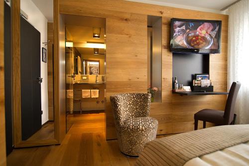 a room with a chair and a television on a wall at Sperber Bräu - 3-Sterne-Superior Hotel mit Gasthof und eigener Brauerei - kein Ruhetag in Sulzbach-Rosenberg