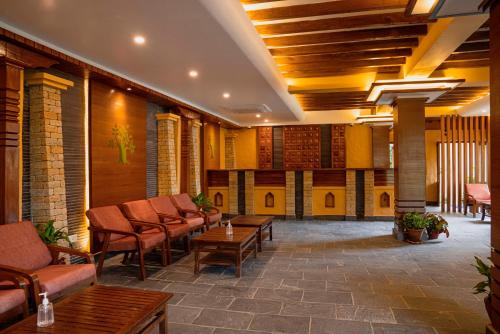 a lobby with chairs and tables in a building at Bar Peepal Resort in Pokhara