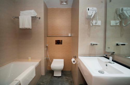 
a bathroom with a toilet, sink, and bathtub at Bar Peepal Resort in Pokhara
