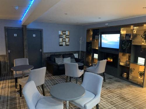 un soggiorno con tavoli, sedie e TV di The Davron Hotel a Fraserburgh