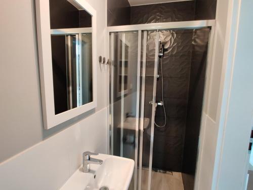 a bathroom with a shower and a sink and a mirror at Ostrowo Plaza in Ostrowo