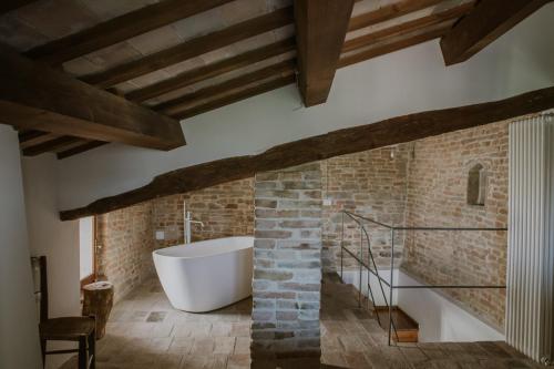 La salle de bains est pourvue d'une baignoire et d'un mur en briques. dans l'établissement Borgo Loretello, à Loretello