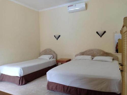 a room with two beds in a room at Hotel Mutiara Baru in Batu