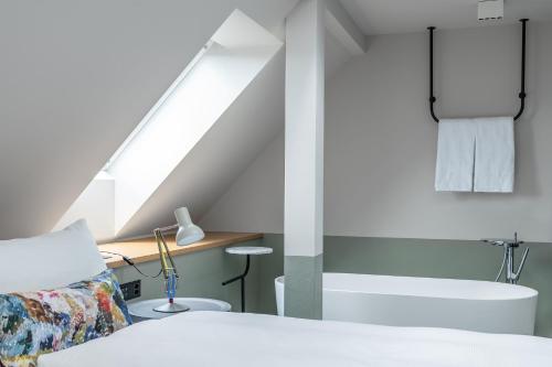 ein Schlafzimmer mit einem Bett und ein Badezimmer mit einem Waschbecken in der Unterkunft Sorell Hotel City Weissenstein - Boutique Hotel in St. Gallen