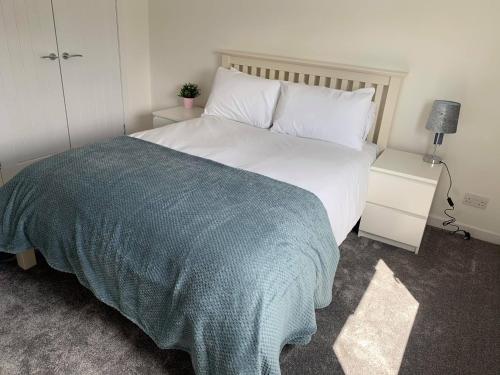 a bedroom with a large bed with a blue blanket at Town Centre Apartment in Hawick