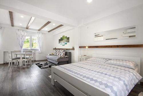 a white bedroom with a bed and a table at Studio apartments Kaya in Čatrnja