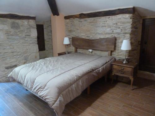 ein Schlafzimmer mit einem großen Bett und einer Steinmauer in der Unterkunft Os NOVOS in Villalba