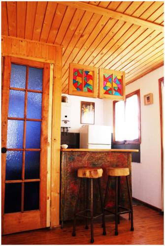 a kitchen with a counter and stools in a room at Cabañas La Magia de Isla Negra in Isla Negra