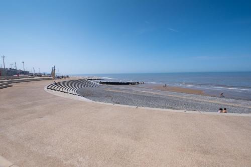 a beach with people walking on the sand and the ocean at Seahawk Holiday Apartments in Cleveleys