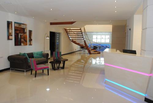 a lobby with a staircase and a couch and chairs at Hotel Kilton in San Carlos de Bariloche
