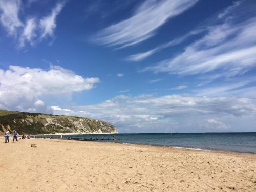 a beach with people on the sand and the ocean at 225 Buttercup Swanage Bay View - Vacation Home in Swanage