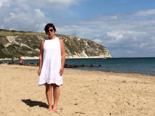 a man in a white dress standing on the beach at 225 Buttercup Swanage Bay View - Vacation Home in Swanage