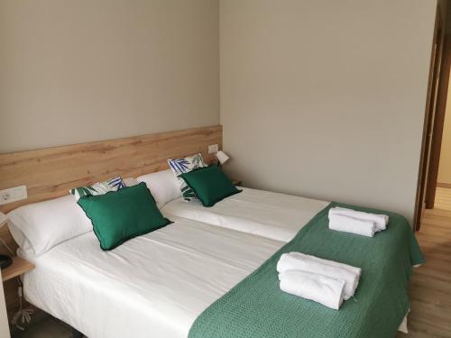 two beds in a room with green and white pillows at Km101 in Baamonde