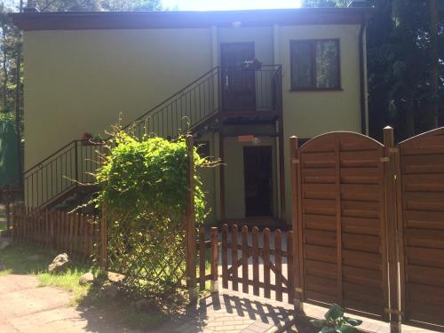 a house with a wooden fence and a staircase at Domek pod świerkami 1 in Skorzęcin