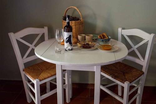 a white table with a bottle of wine and a basket at Arsinoe - Cosy guesthouse- in Methana