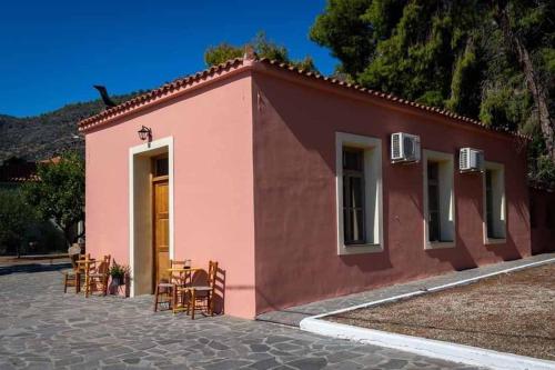 a small pink building with a table and chairs at Arsinoe - Cosy guesthouse- in Methana