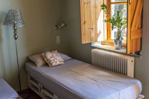 a bedroom with a bed with a lamp and a window at Arsinoe - Cosy guesthouse- in Methana