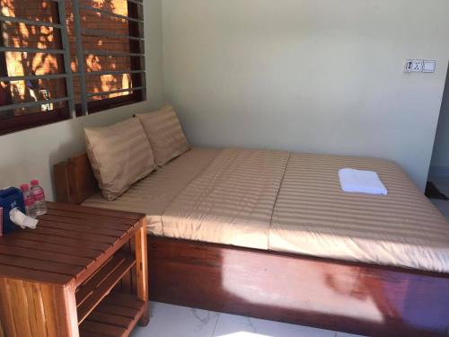 Manel Guesthouse and Restaurant في سينمونوروم: سرير مع اطار خشبي في الغرفة