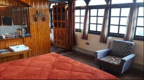 - une chambre avec un lit, une chaise et des fenêtres dans l'établissement Tip Top Gujarati House, à Gangtok