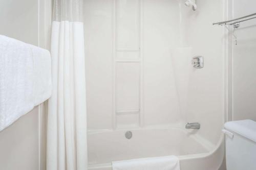 a white bathroom with a shower and a toilet at Ramada by Wyndham in Quesnel