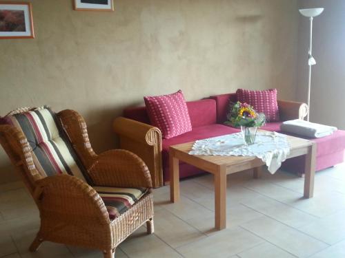 a living room with a pink couch and two chairs at Ferienhof am Nationalpark in Schöneberg