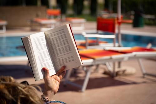 a person holding a book in front of a pool at Borgo Verde in Vada