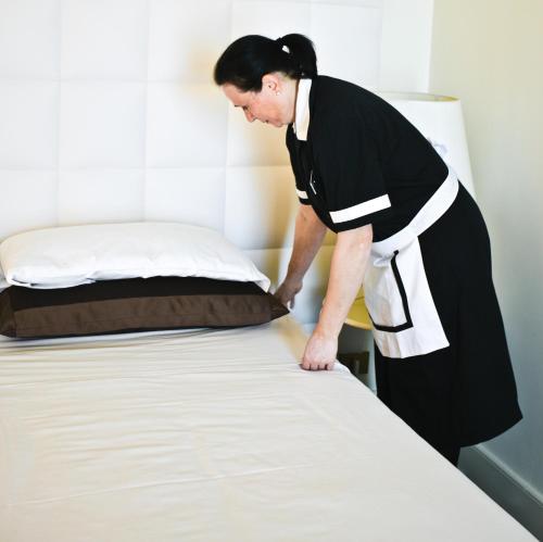 a woman is making a bed in a room at Etrusco Arezzo Hotel - Sure Hotel Collection by Best Western in Arezzo