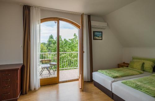1 dormitorio con 1 cama y puerta a un balcón en Balaton Vendégház, en Balatonfüred