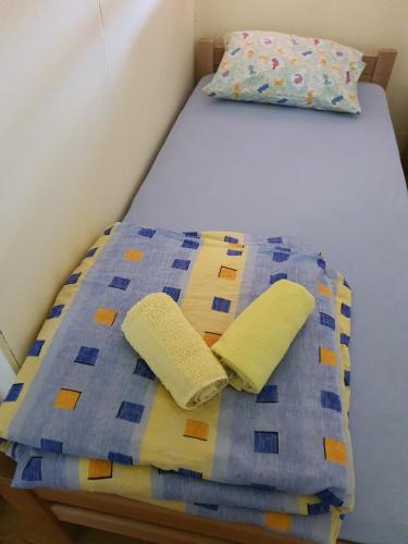a bed with a blue and yellow quilt and two pillows at Apartman Petra in Nova Varoš
