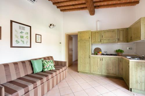 a kitchen with wooden cabinets and a couch in a room at Borgo Verde in Vada