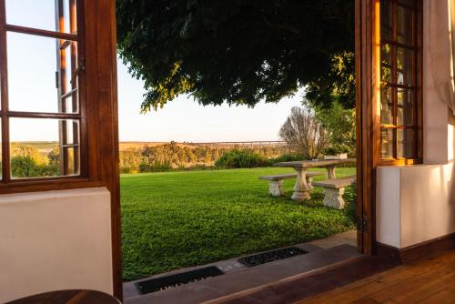 an open door to a garden with a bench outside at Melkboomsdrift Guest House & Conference Centre in Vredendal
