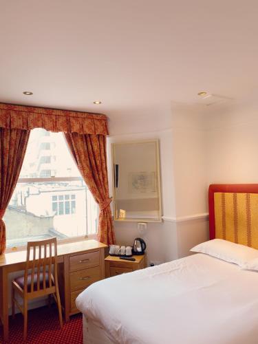 a bedroom with two beds and a desk and a window at Hyde Park Radnor Hotel B&B in London