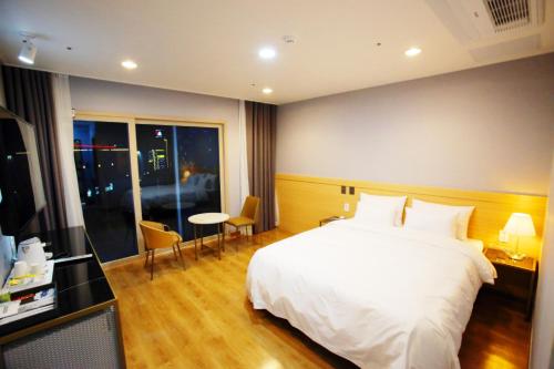 a bedroom with a white bed and a table and chairs at Hotel Haemaru in Gwangyang