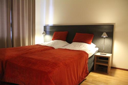 una camera da letto con un grande letto con piumone rosso di Ylläs Majoitus Chalets 8, 8101 a Ylläsjärvi