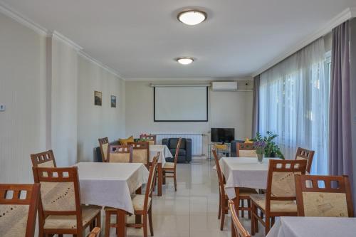 a dining room with tables and chairs and a screen at Villa Harmónia Panzió in Visegrád