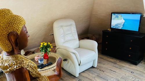 a woman sitting in front of a chair and a television at Salzoasen Apartment in Bad Schwartau