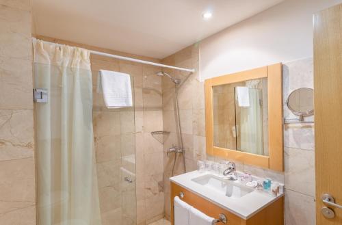 a bathroom with a shower and a sink and a mirror at Hotel LIVVO Corralejo Beach in Corralejo