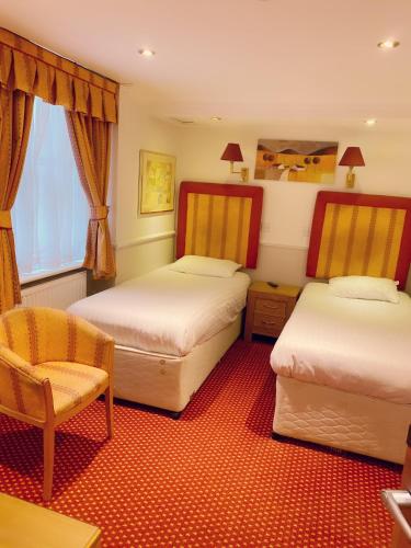 a hotel room with two beds and a chair at Hyde Park Radnor Hotel B&B in London