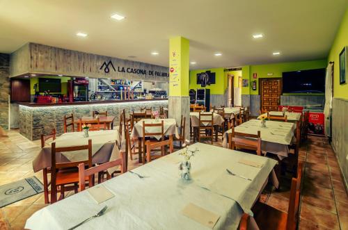 un restaurante con mesas y sillas blancas y una barra en LA CASONA DE PALMIRA en Caín