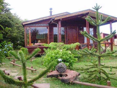 eine Blockhütte in einem Garten mit Pflanzen in der Unterkunft Rio Maullin Lodge in Puerto Varas