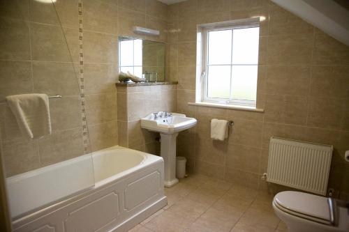 La salle de bains est pourvue d'une baignoire, d'un lavabo et de toilettes. dans l'établissement Rivermount House, à Kinsale
