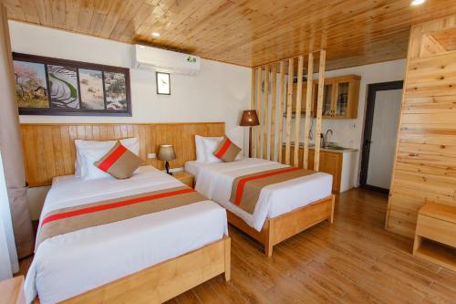 two beds in a room with wooden walls and wooden floors at SaPa Retreat Condotel in Sa Pa
