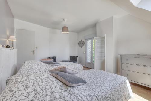 a white bedroom with two beds and a dresser at Gite de Lizy in Anizy-le-Grand