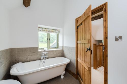 a white bath tub in a bathroom with a window at Hollyhock House in Stonesfield
