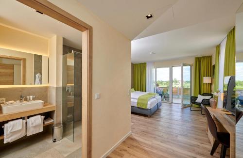 ein Hotelzimmer mit einem Bett und einem Bad in der Unterkunft Bachhof Resort Hotel in Kirchroth