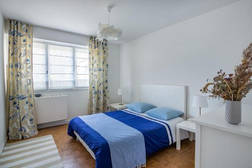 Un dormitorio con una cama con almohadas azules y una ventana en Le Saint É, en Dinard