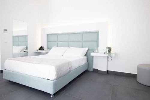 a white bedroom with a large bed and a table at GRAND HOTEL SERAPIDE in Pozzuoli